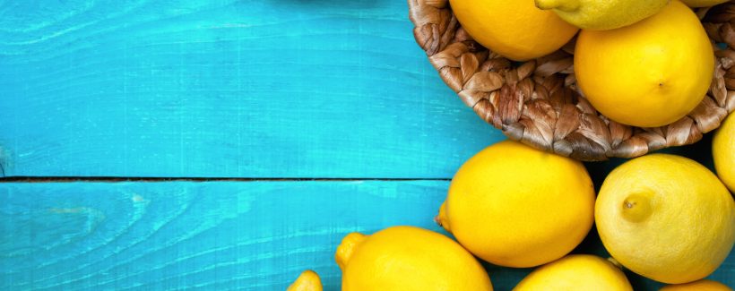 Yellow colorful lemons on the bright cyan wooden table horizontal